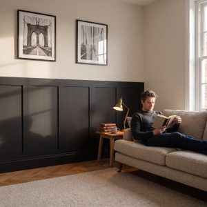Paintable 1.2m MDF Wall Panel Kit installed as half-height wall panelling behind a sofa in a modern living room.