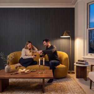 Smokey Blue Melamine Acoustic Wall Panels installed vertically behind a mustard sofa in a contemporary lounge interior.