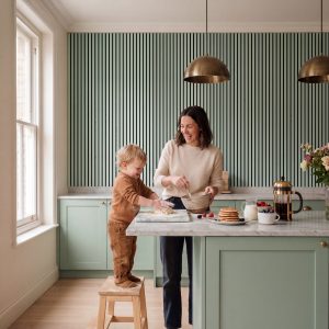 Sage Green Melamine Acoustic Wall Panels installed vertically in a modern kitchen with marble worktops and pendant lighting.
